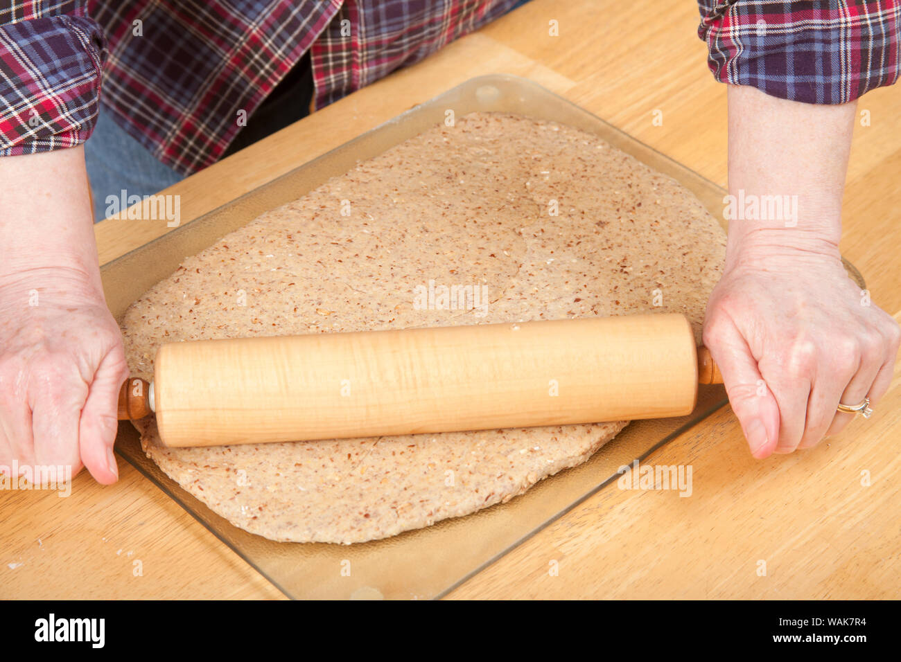 Frau rolling ball von Brotteig mit einem Nudelholz, um es zu glätten, bevor er sich in einen Laib Brot. (MR) Stockfoto