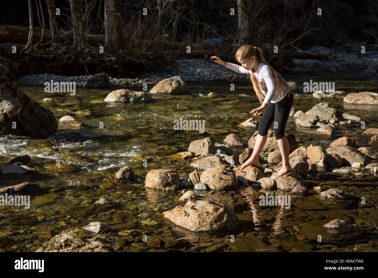 Olallie State Park, in der Nähe von North Bend, Washington State, USA. Neun Jahre alten Mädchen Balancing, wie Sie auf die Felsen in der flachen Snoqualmie Fluss steigt. (MR) Stockfoto