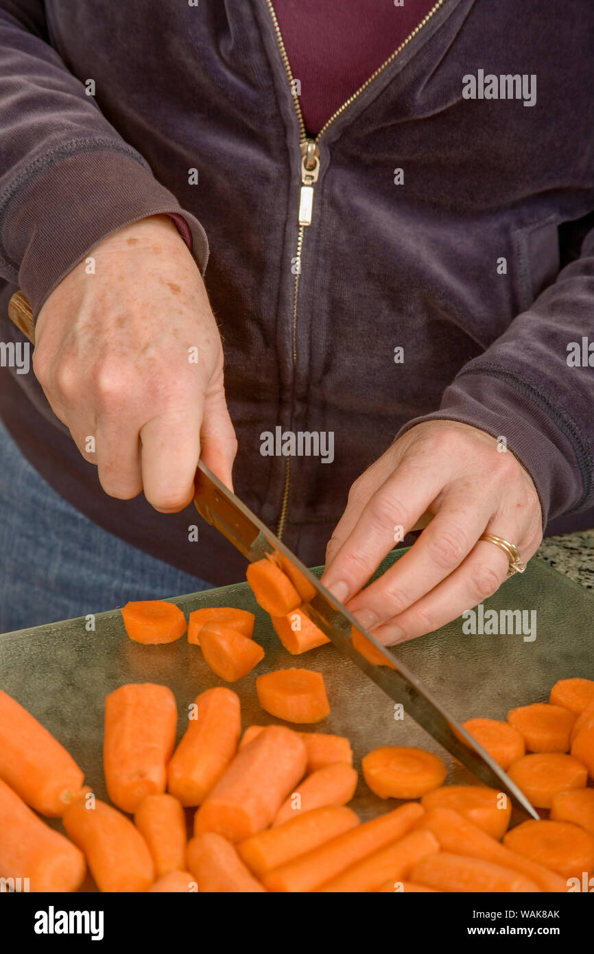 Frau hacken Karotten mit einem Messer in der Vorbereitung für blanchieren und einfrieren. (MR) Stockfoto