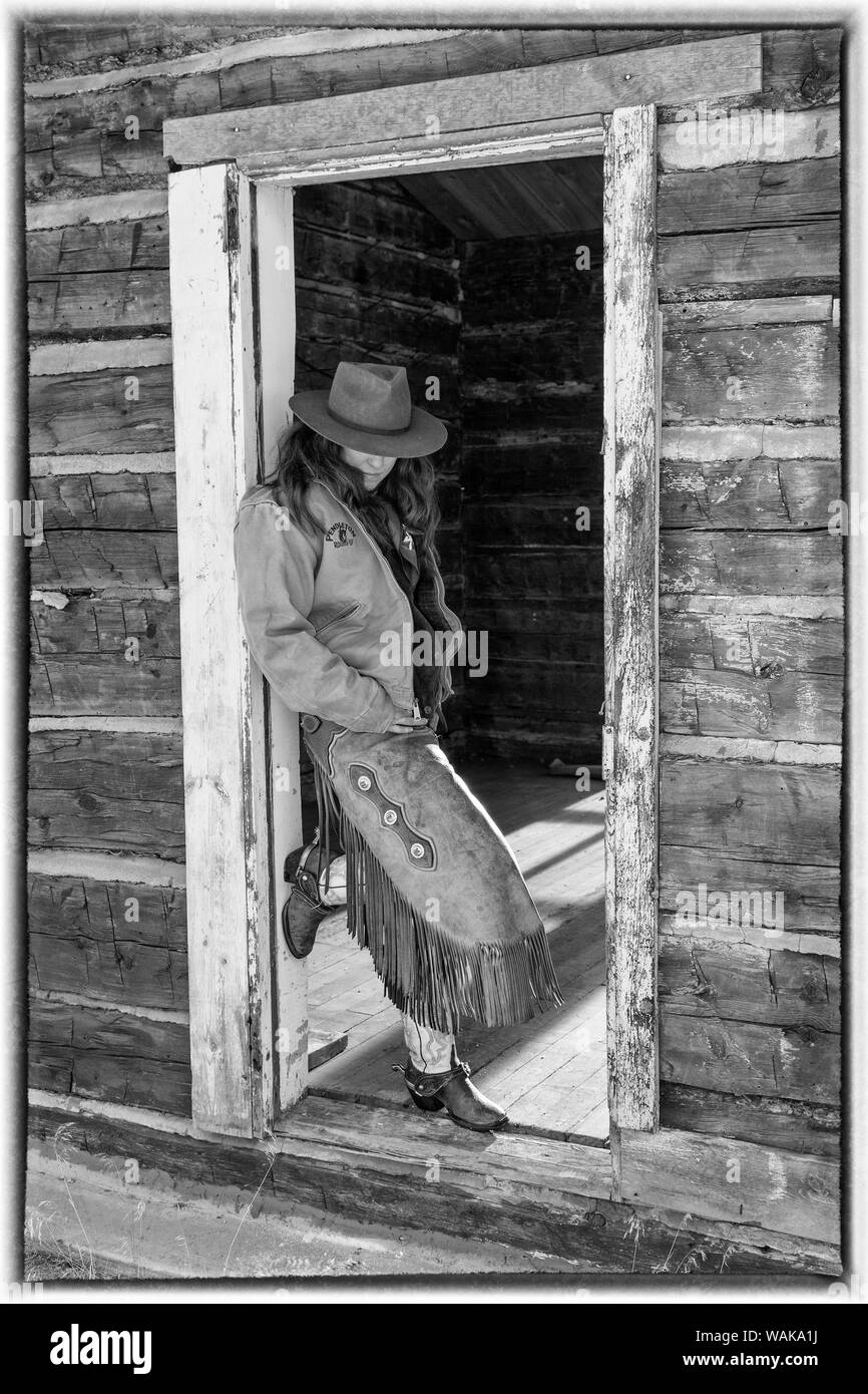 Reiten und Fahren im Winter auf Versteck Ranch, Shell, Wyoming. Cowgirl im Eingang des alten Blockhaus. (MR) Stockfoto