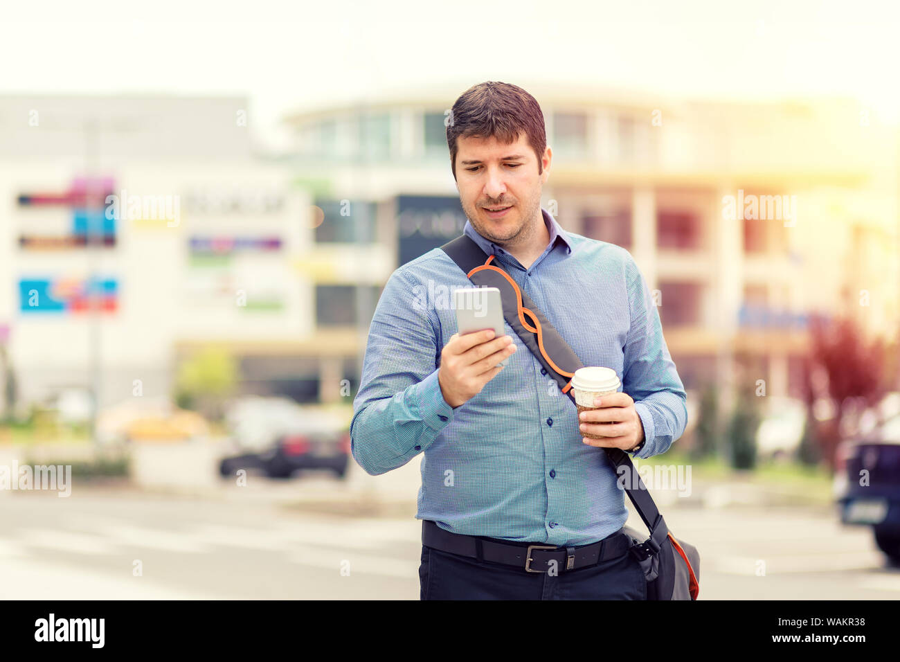 Lächelnd reifer Mann mit Handy beim Gehen auf die Straße, um zu gehen zu arbeiten - Glückliche unbeschwerte freier Mann trinkt Kaffee beim Versand von Nachrichten Stockfoto