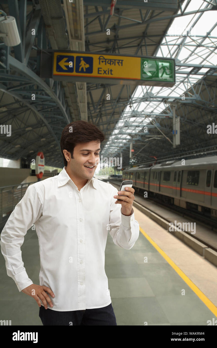 Junger Mann SMS auf dem Mobiltelefon auf einer U-Bahn-Plattform Stockfoto