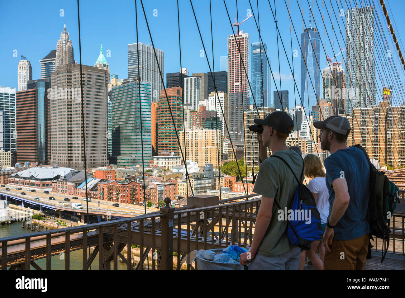 New York Touristen, Blick auf eine Familie, die auf der Brooklyn Bridge und Blick über den East River in Richtung Lower Manhattan Skyline, New York City, USA Stockfoto