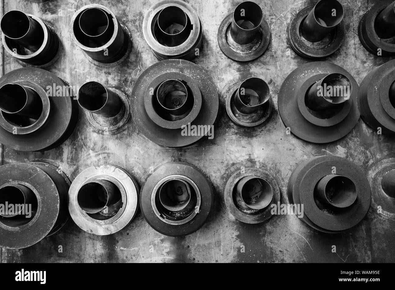 Ein schwarz-weiß Bild eines schmutzig schmutzige Wand mit Ringen aus Stahl und stirbt auf Stahlrohre in der Werkstatt montiert Stockfoto