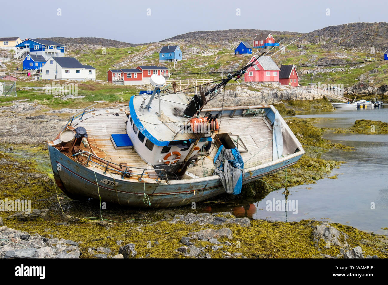 Strände altes Fischerboot am Meer im Dorf Hafen mit traditionellen Holzhäusern auf der Insel Hang. Itilleq, Qeqqata, Grönland Stockfoto