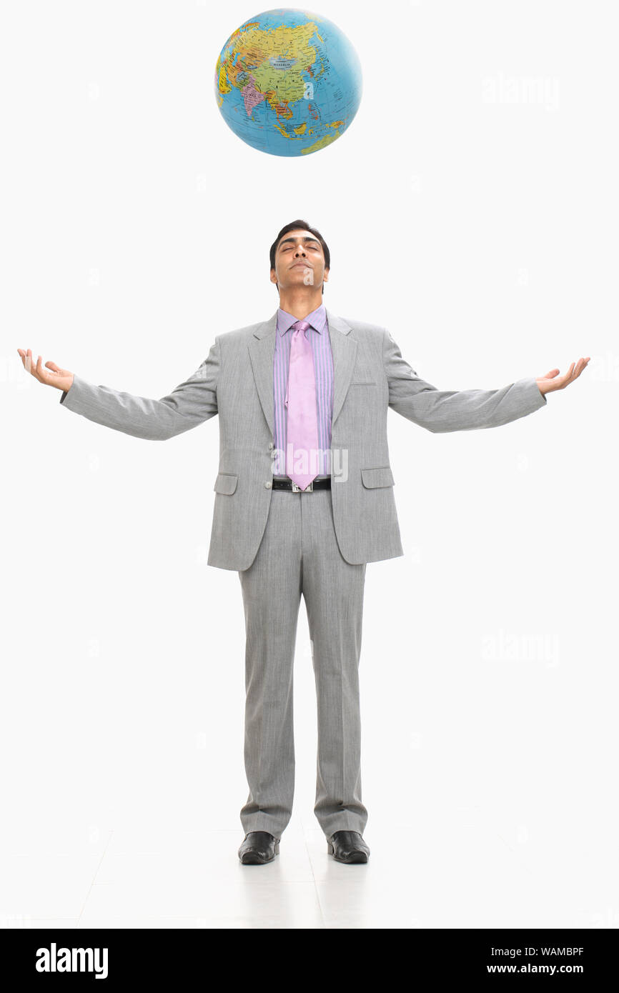 Geschäftsmann steht mit ausgestrecktem Arm und Globus über dem Kopf Stockfoto