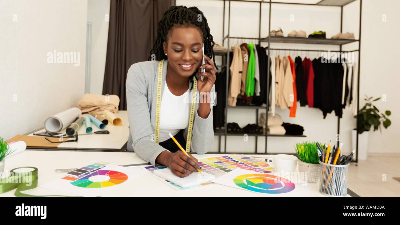 Junge schwarze Fashion Designer diskutieren Kauf mit Client per Telefon Stockfoto