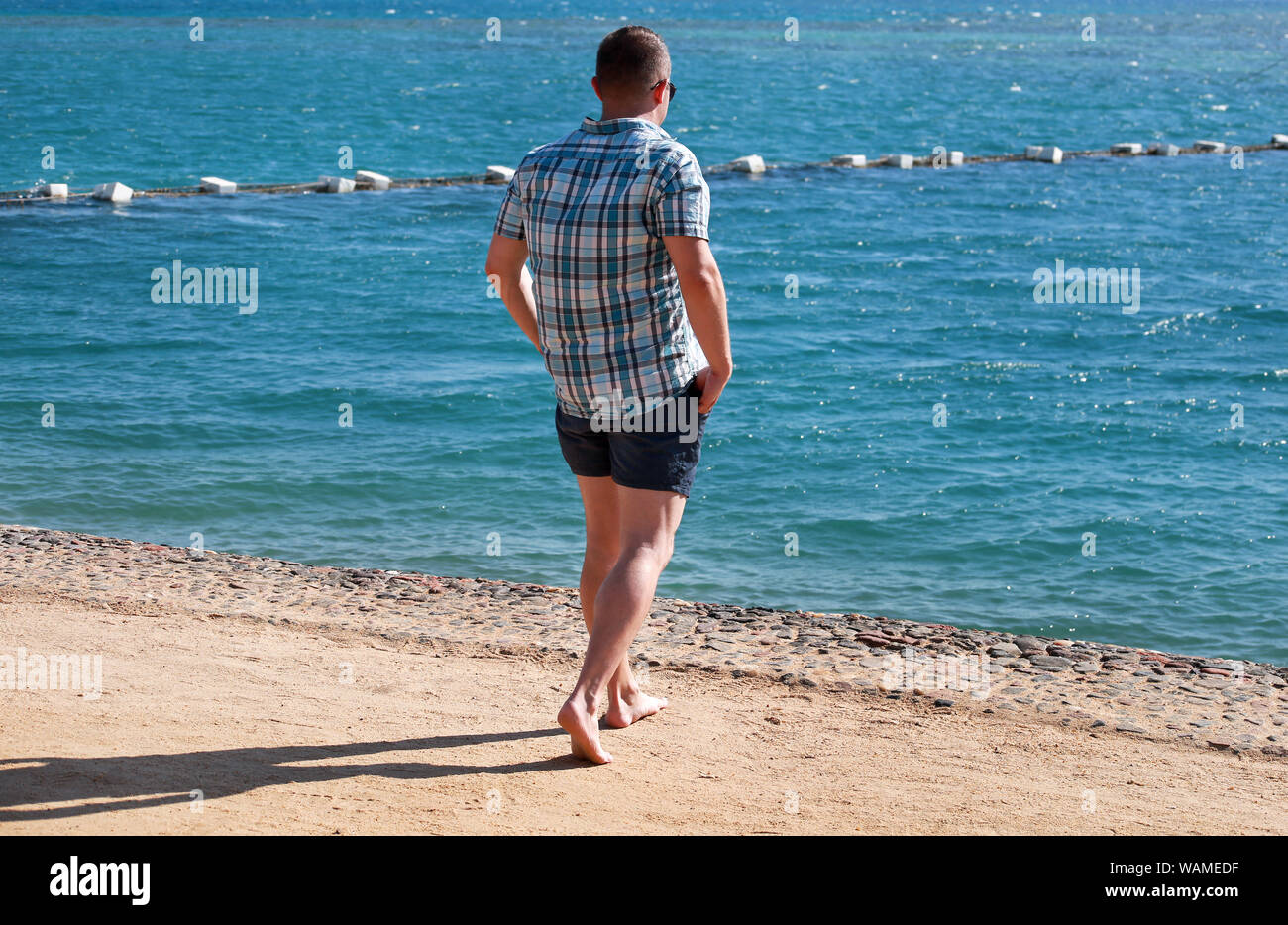 Männliche Touristen und Reisenden zu Fuß, am Sandstrand von Hotel Resort Posing, genießt Meerblick Umwelt, Natur, Landschaft, Panorama, Horizont. Stockfoto
