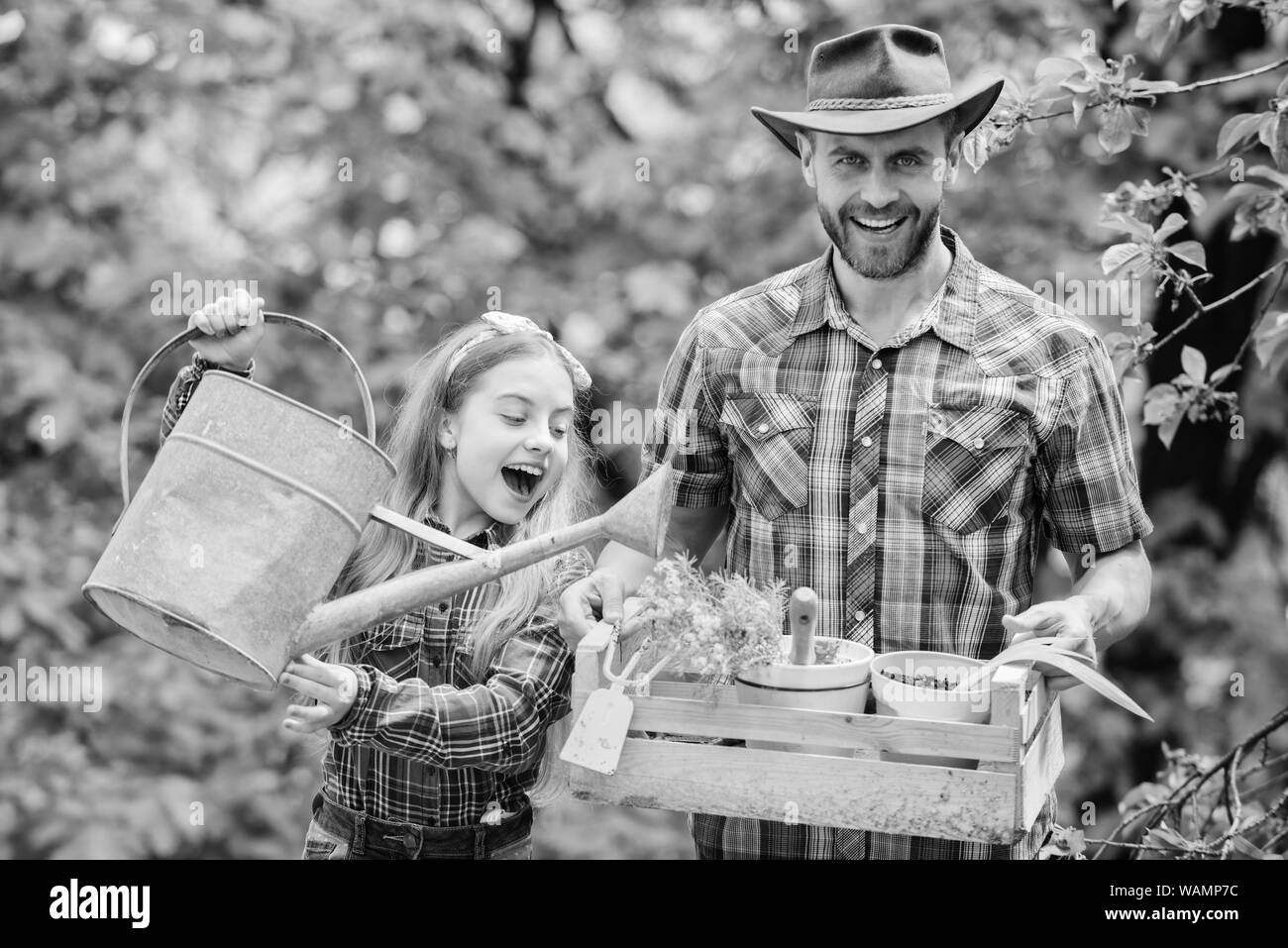 Frühling Dorf Land. Kleines Mädchen und glücklicher Mensch Vati. Tag der Erde. Ökologie. Gießkanne und Schaufel. Farm der Familie. Vater und Tochter auf der Ranch. Arbeiten mit Blumen. Stockfoto