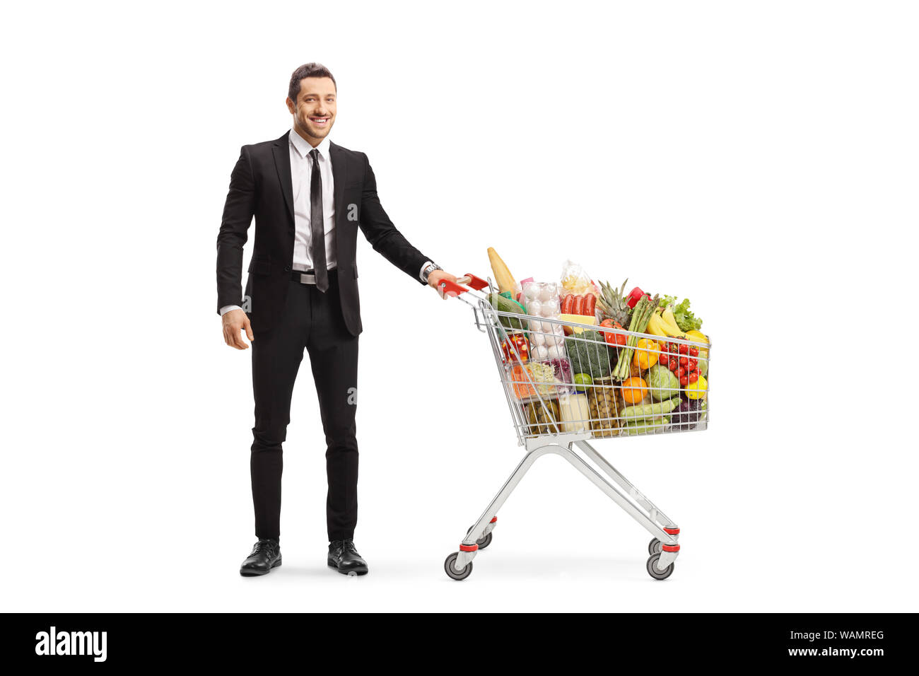 In voller Länge Porträt ein Geschäftsmann mit einem Einkaufswagen mit Lebensmitteln auf weißem Hintergrund posiert Stockfoto