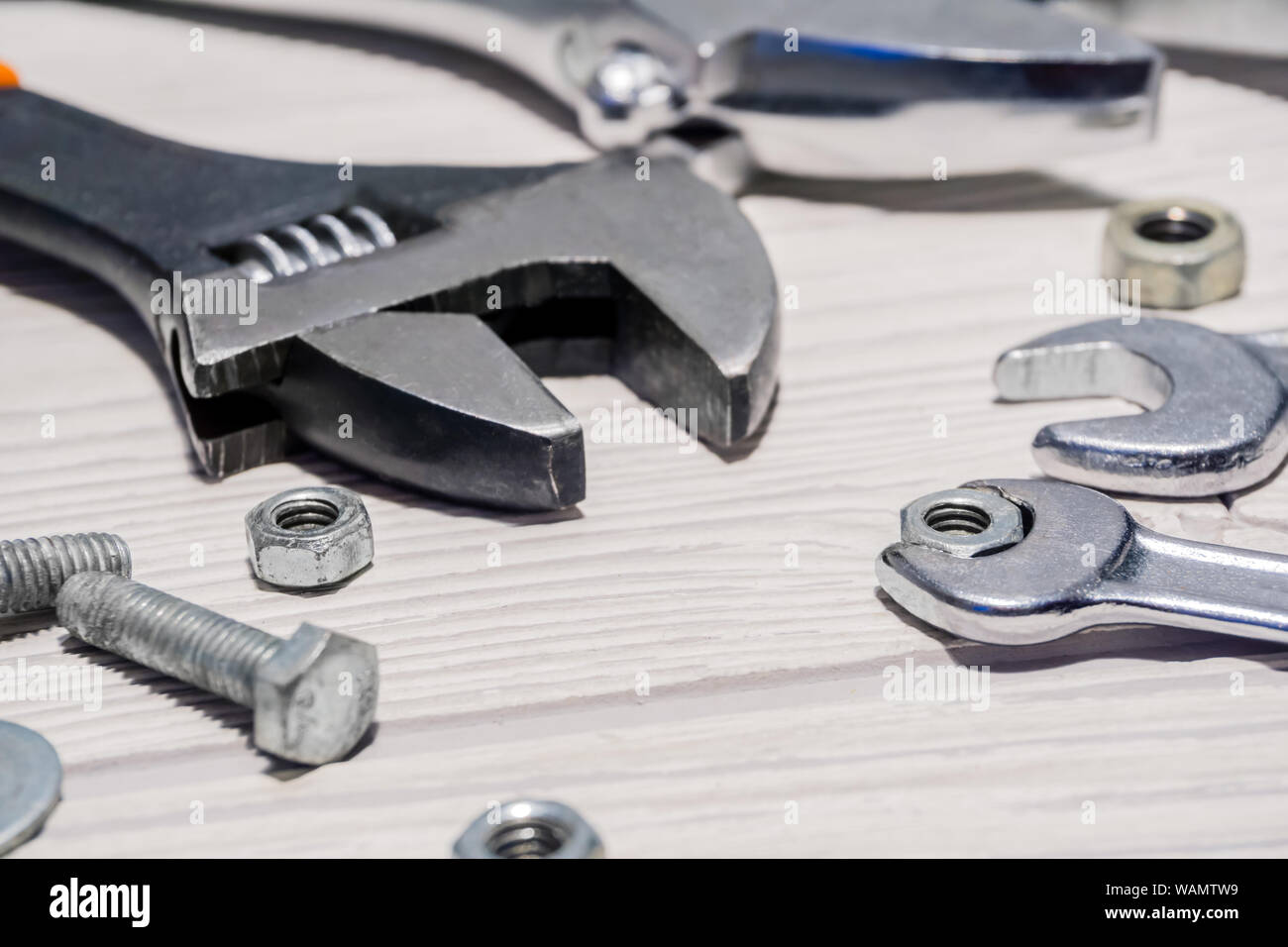 Verstellbarer Schraubenschlüssel und herkömmlichen Schlüsseln, Muttern und Schrauben sind auf dem Tisch in der Nähe von Stockfoto
