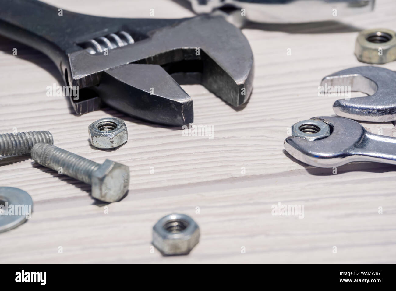 Verstellbarer Schraubenschlüssel und herkömmlichen Schlüsseln, Muttern und Schrauben sind auf dem Tisch in der Nähe von Stockfoto