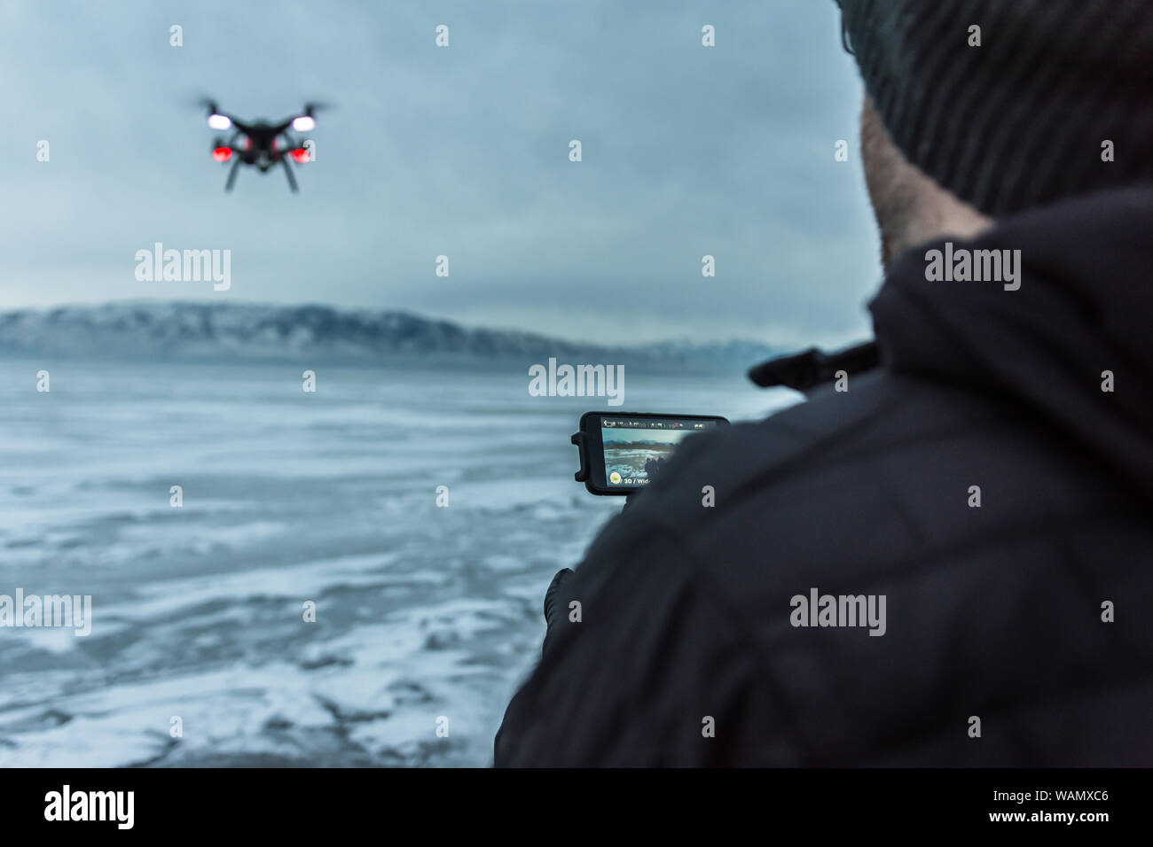 Über die Schulter geschossen der kaukasischen männlichen Fliegen quadcopter über Utah Lake, USA eingefroren Stockfoto