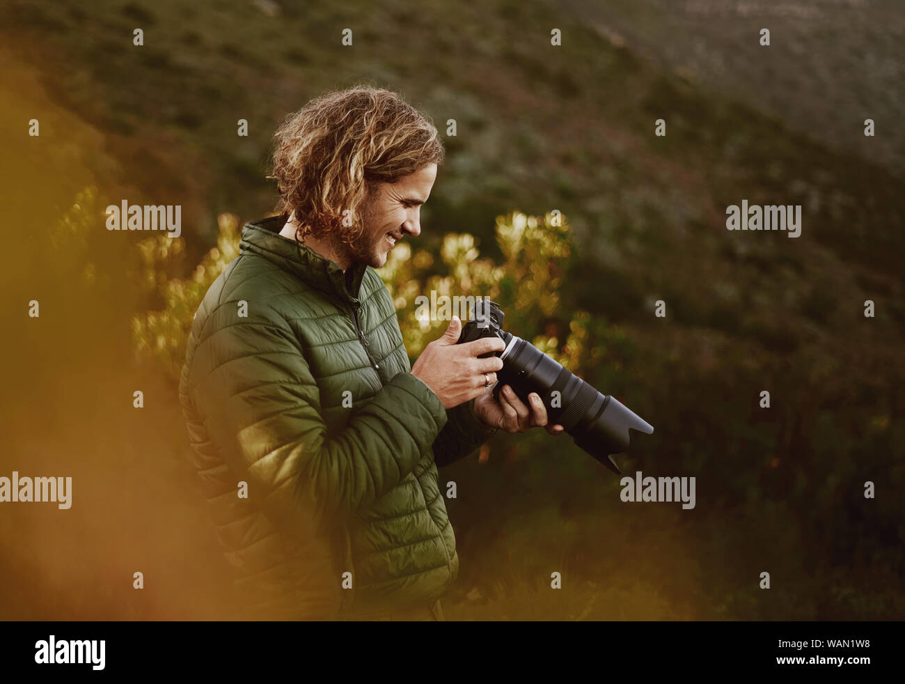 Lächelnd männlichen Fotograf prüfen Fotos auf der Kamera Stockfoto