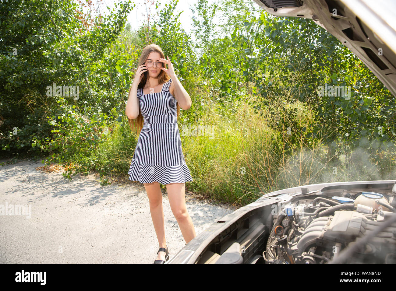 Die junge Frau brach das Auto während der Reise auf dem Weg zum Rest. Sie versucht zu beheben, die durch Ihre eigene gebrochen oder zu trampen. Nervös. Wochenende, Probleme auf der Straße, Urlaub. Stockfoto