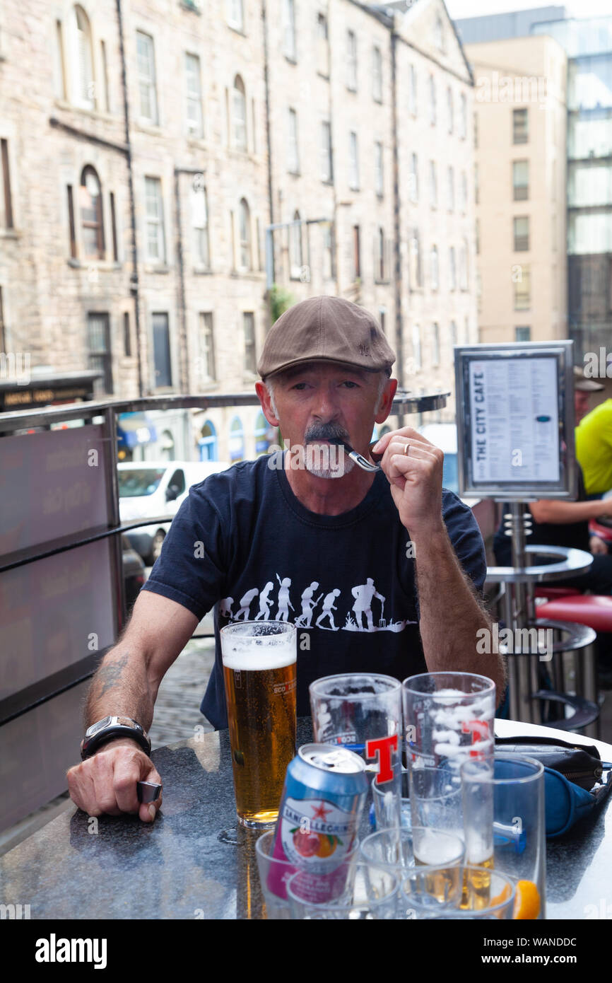 Ein Mann im mittleren Alter Rauchen einer Pfeife mit einem Pint Lager vor ihm. Stockfoto