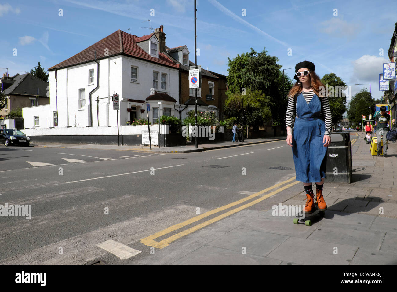 Stilvoll jugendlich Junge Frau mit Sonnenbrille und rote Stiefel auf Skateboard in West Green Road street in Sieben Schwestern Tottenham London N16 UK KATHY DEWITT Stockfoto