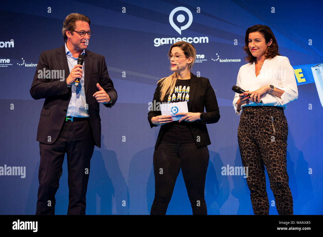 Köln, Deutschland. 20 Aug, 2019. Gamescom 2019: Moderator Melek Balgün (M) Gespräche mit Andreas Scheuer (links), Bundesminister für Verkehr und digitale Infrastruktur, und Dorothee Bär, Staatsminister im Bundeskanzleramt und Beauftragten der Bundesregierung für Angelegenheiten, bei der Eröffnung. Die gamescom ist die weltweit größte Messe für Computer- und Videospiele, der koelnmesse in Köln, Deutschland, vom 20. bis 24. August 2019. Photocredit: Christian Lademann Stockfoto