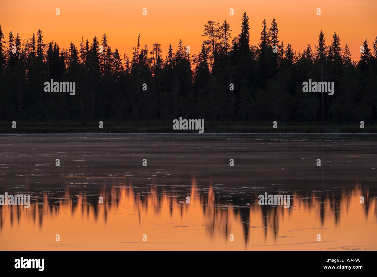 Intensive Sonnenuntergang über dem See in Finnland mit schönen Reflexionen Stockfoto