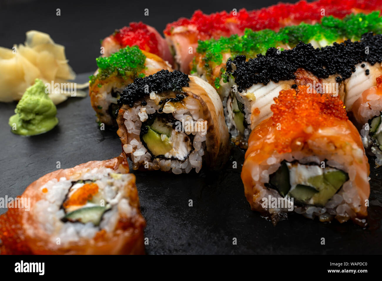 Sushi Roll Philadelphia mit Lachs, geräucherter Aal, Avocado, Frischkäse auf schwarzem Hintergrund. Sushi Menü. Japanisches Essen. Stockfoto