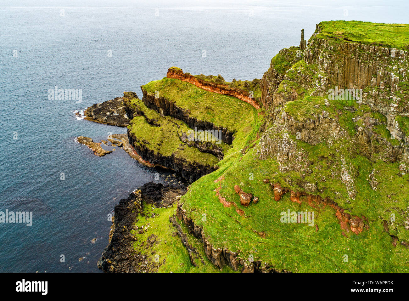 Nordirland, Großbritannien. Klippen am Atlantik in der Grafschaft Antrim mit sichtbaren geologischen Schichten, und vulkanischen Basalt Bildung von natürlichen sechseckige Pol Stockfoto