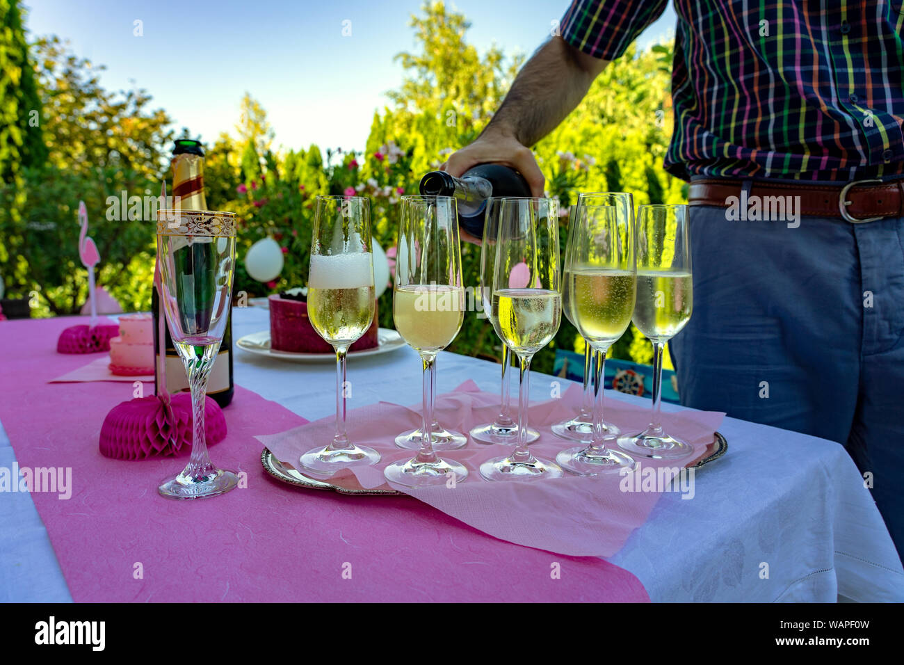 Gießen Sie Champagner auf eine rosa Party im Freien. Stockfoto