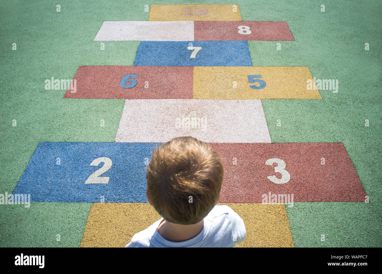 Jungen lernen Zahlen an Gummi Hopse. Zahlen auf dem Bürgersteig. Frühe Bildung in Mathematik-, Schreib- und Rechenfertigkeiten Konzept für Kinder Stockfoto