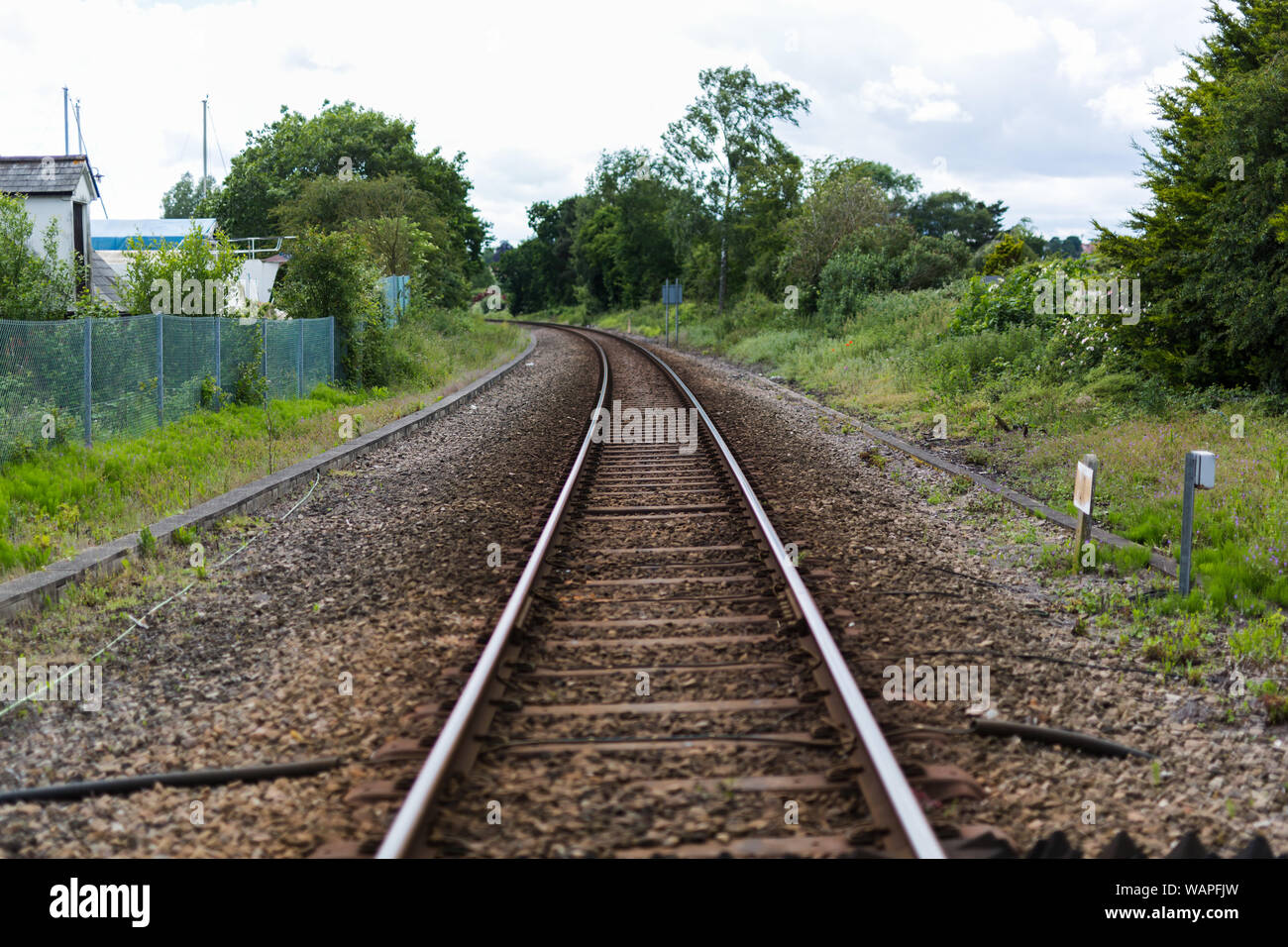 Ein einziger Satz von Bahngleisen führt zu einem Fluchtpunkt am Horizont, die Bahnlinie schneidet durch ländliche britische Landschaft Stockfoto