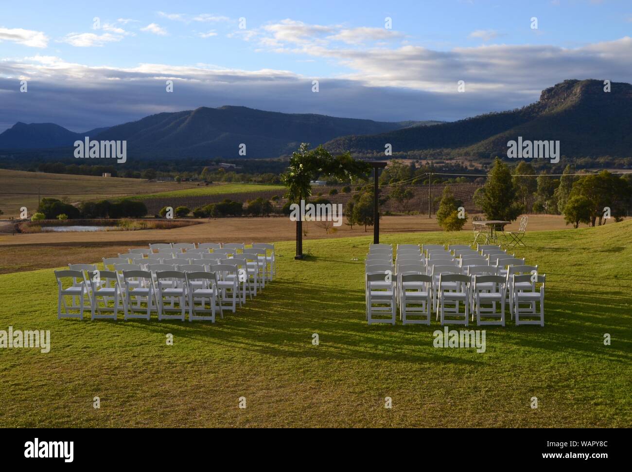 Hochzeit arch und Sitzgelegenheiten bereit für eine Verpflichtung Zeremonie mit Blick auf die Weinberge und Hügel von NSW Hunter Valley Stockfoto
