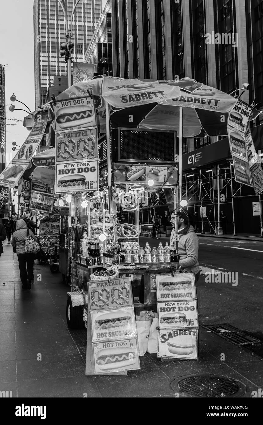 Straßenhändler in New York City Verkauf von Würstchen und Brezeln aus seinem Street Food Warenkorb. Stockfoto