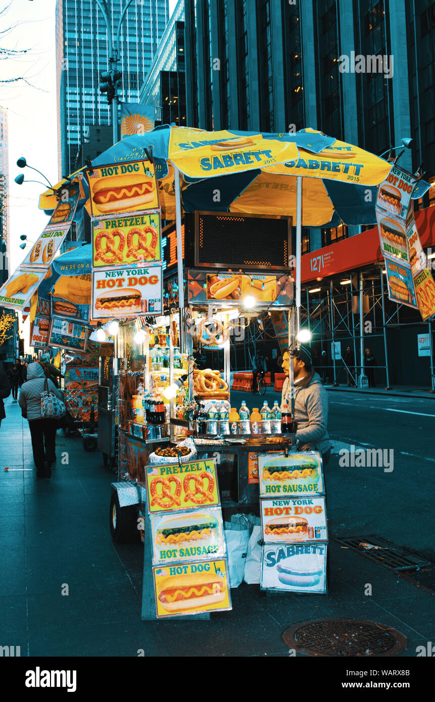 Straßenhändler in New York City Verkauf von Würstchen und Brezeln aus seinem Street Food Warenkorb. Stockfoto
