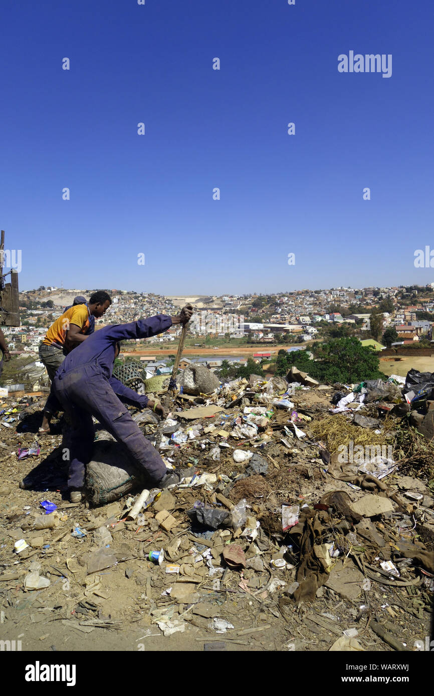Männer drängeln Papierkorb über die Seite der Straße in eine Schlucht, zentrale Antananarivo, Madagaskar. Keine MR oder PR Stockfoto