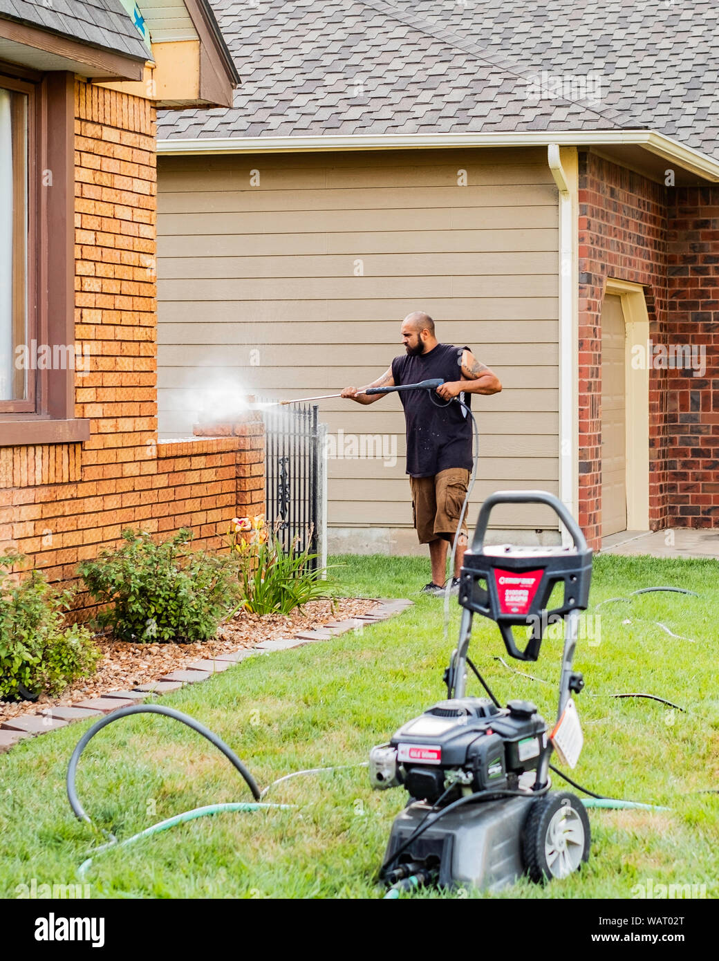 Ein erwachsener hispanischer Mann wäscht Ziegel zur Vorbereitung der Malerei. USA. Stockfoto