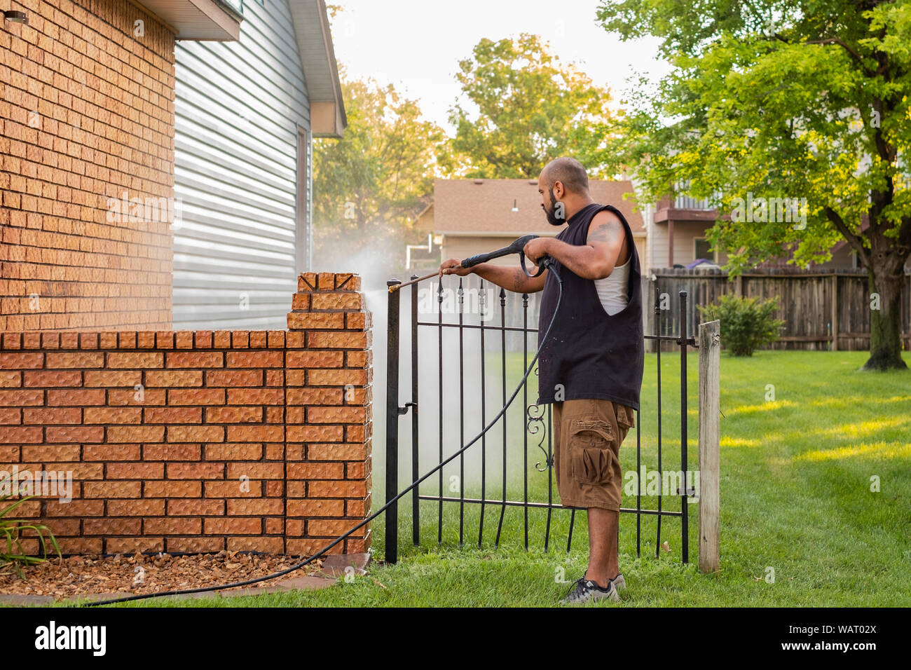 Ein erwachsener hispanischer Mann wäscht Ziegel zur Vorbereitung der Malerei. USA. Stockfoto