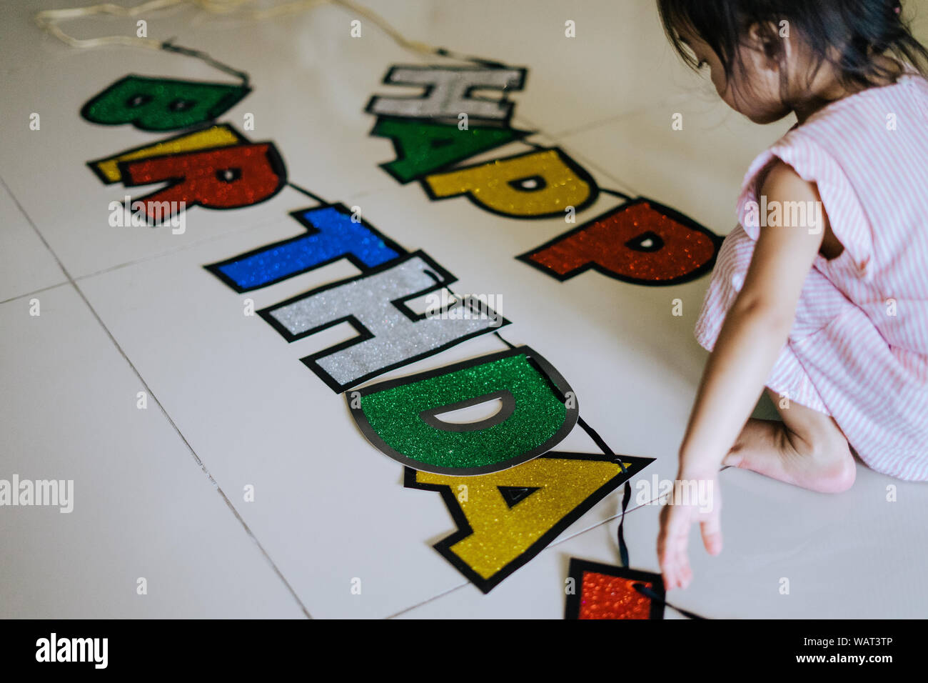 Banner Rechtschreibung Happy Birthday auf dem Boden mit Kleinkind neben ihm sitzen. Stockfoto