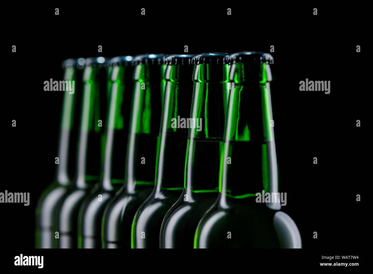 Zeile aus Glas Flaschen Bier auf dunklem Hintergrund Stockfoto
