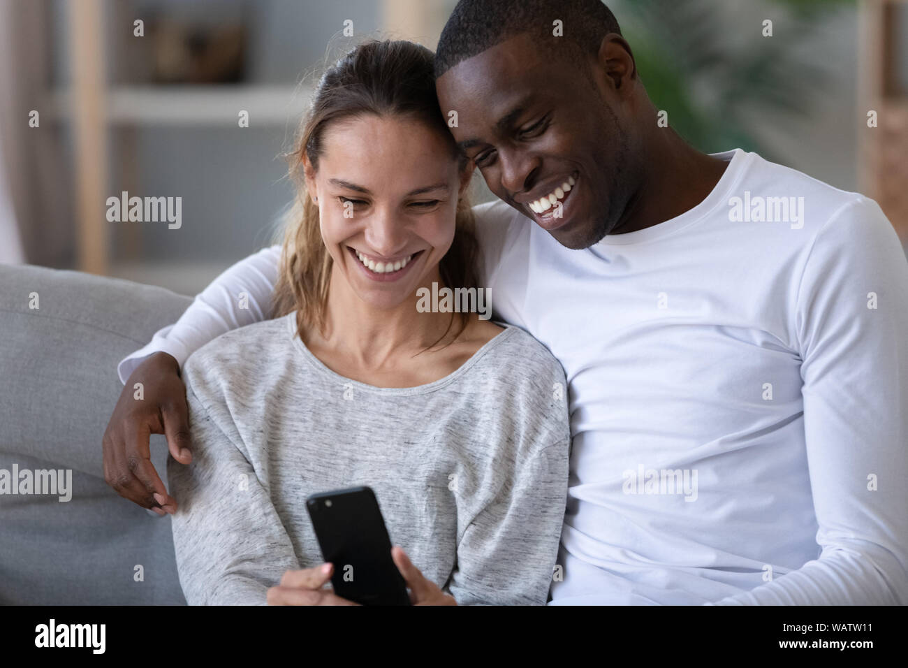 Happy Mixed Race Paar mit Phone unter selfie auf dem Sofa Stockfoto