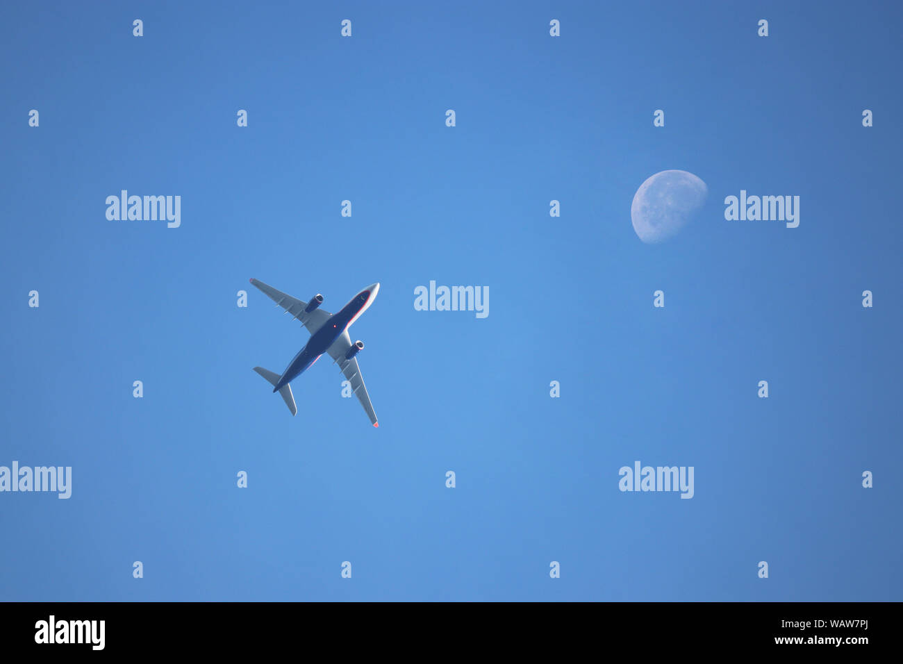 Flugzeug fliegen im blauen Himmel im Hintergrund des abnehmenden Mondes in den Morgen. Kommerzielle zweimotorige Flugzeug, Flugverkehr Konzept Stockfoto