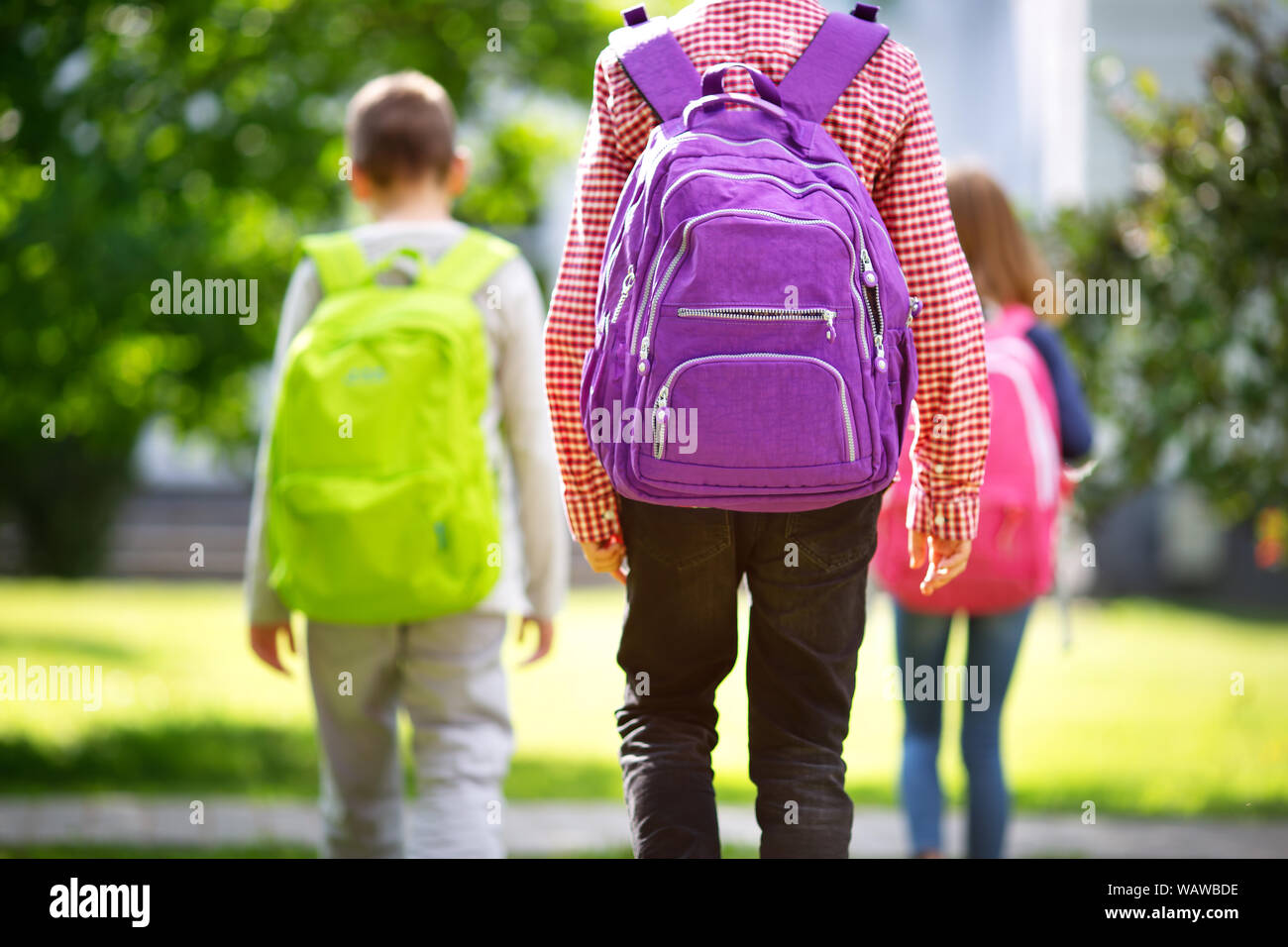Kinder mit Rucksäcken stehen im Park in der Nähe von Schule Stockfoto
