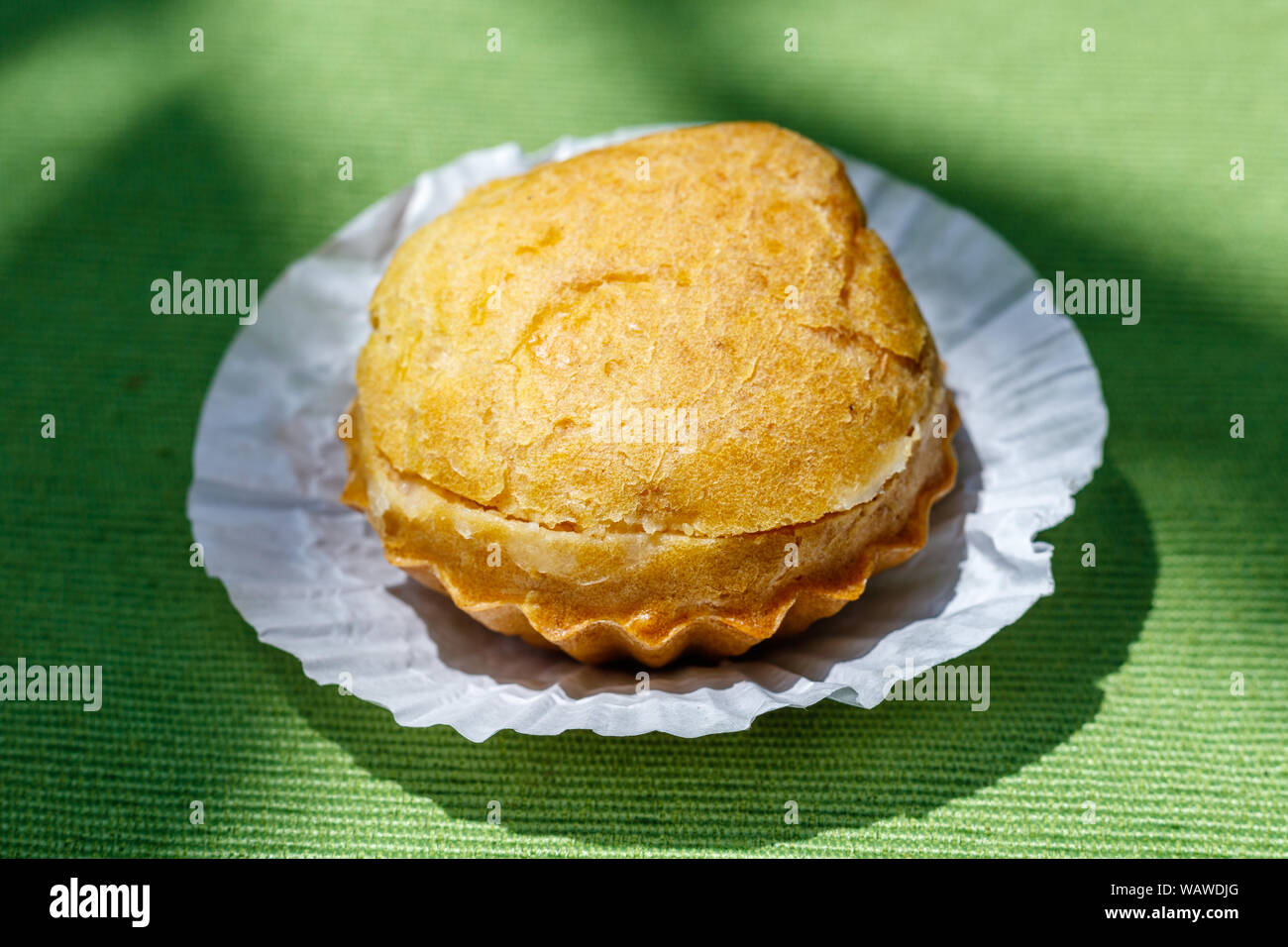 Kue sus (soes) oder Profiteroles mit Vanillesauce. Auf grünem Stoff Hintergrund. Indonesische Dessert, Street Food. Bali, Indonesien. Stockfoto