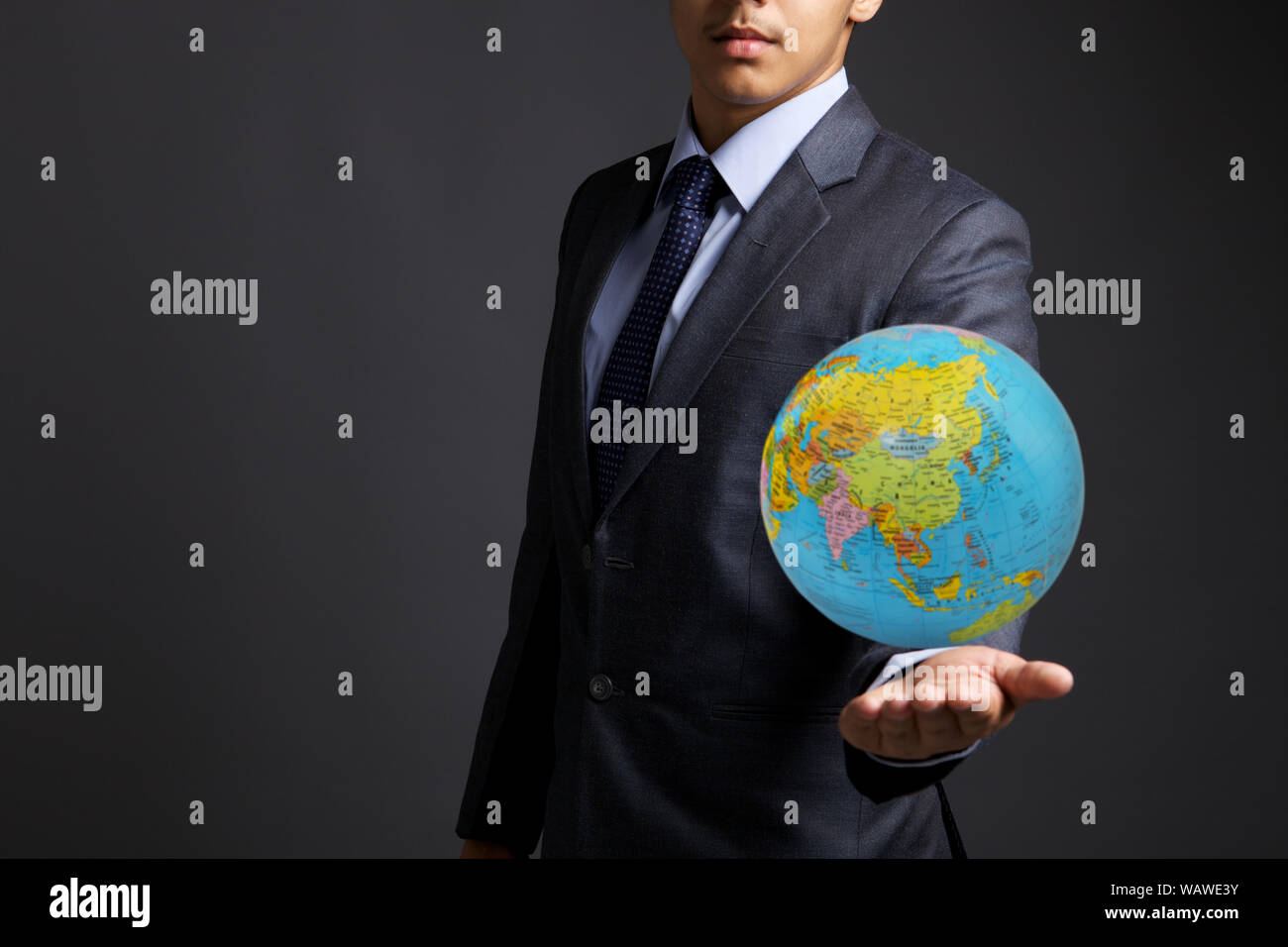 Junger Geschäftsmann zeigt einen Globus Stockfoto