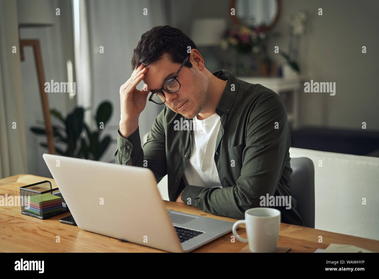 Portrait von Stress Mann traurig auf dem Laptop zu Hause arbeiten Stockfoto