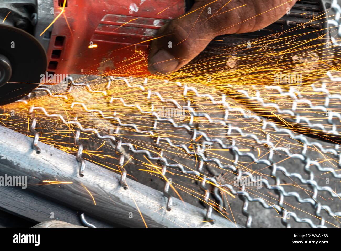 Man Winkelschleifer ohne Schutzabdeckung Schneiden von Metall net Vogelkäfig zu machen. Stockfoto