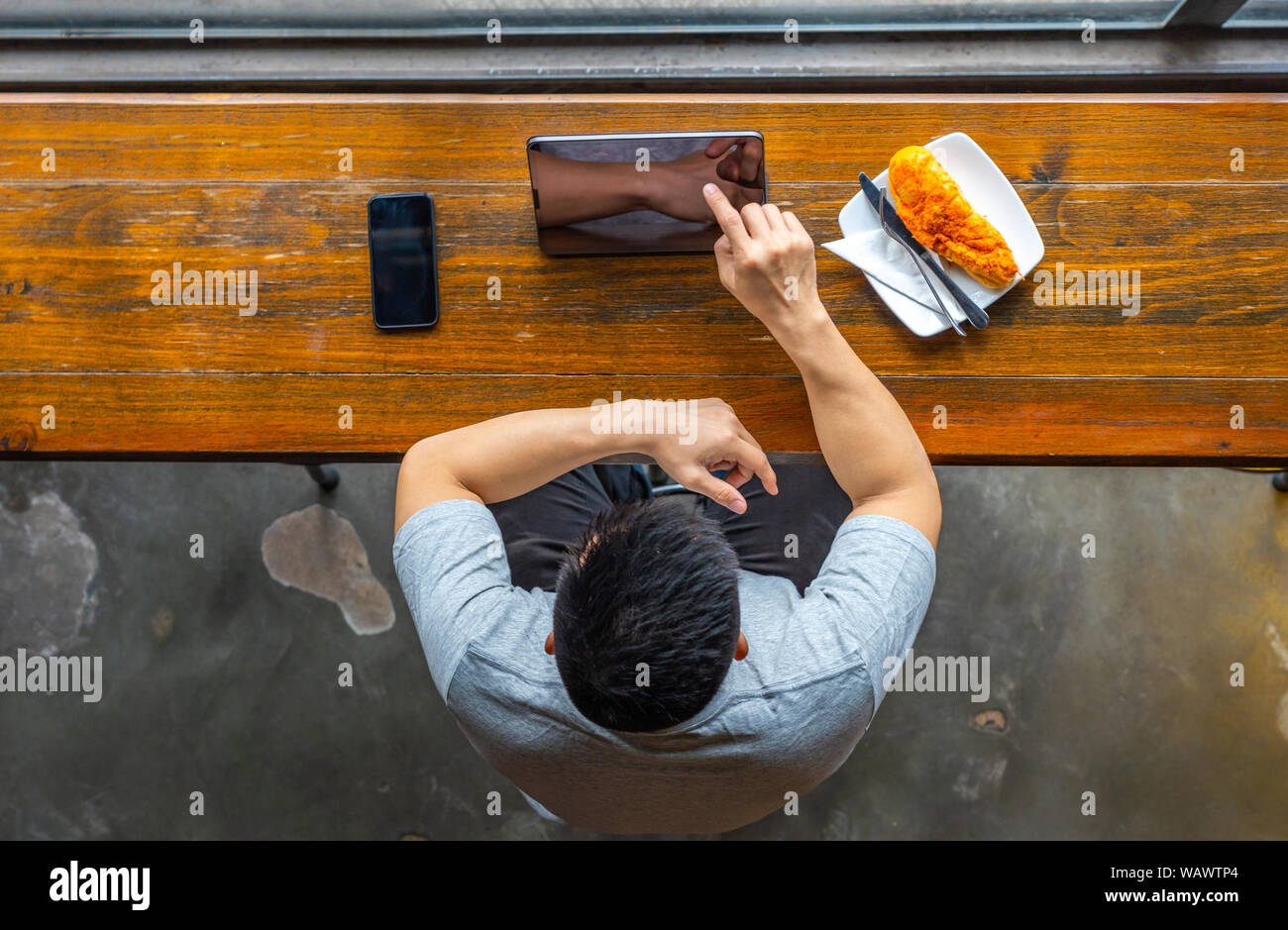 Junge asiatischer Mann Tippen auf Tablet Bildschirm im rustikalen Wirtsstube Stockfoto