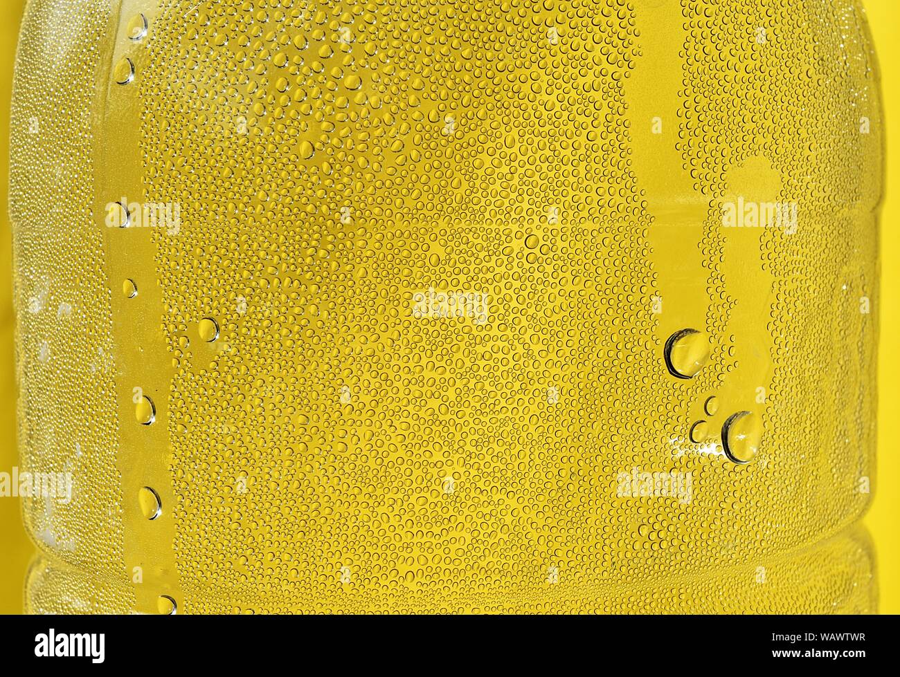Viele Wassertropfen auf der Oberfläche eines transparenten Kunststoff Flasche auf gelben Hintergrund isoliert, abstrakte Textur für Hinzufügen von Text oder Grafik Design Stockfoto