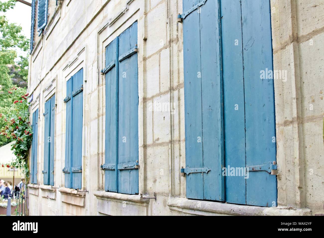 Gebäudefassade mit großen blauen Holzfenstern. Stockfoto