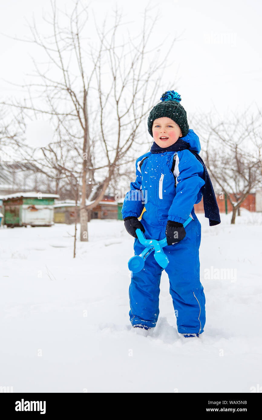 Happy Boy formt und wirft Schneebälle. Winter Spiele an der frischen Luft. Winter Urlaub. Stockfoto