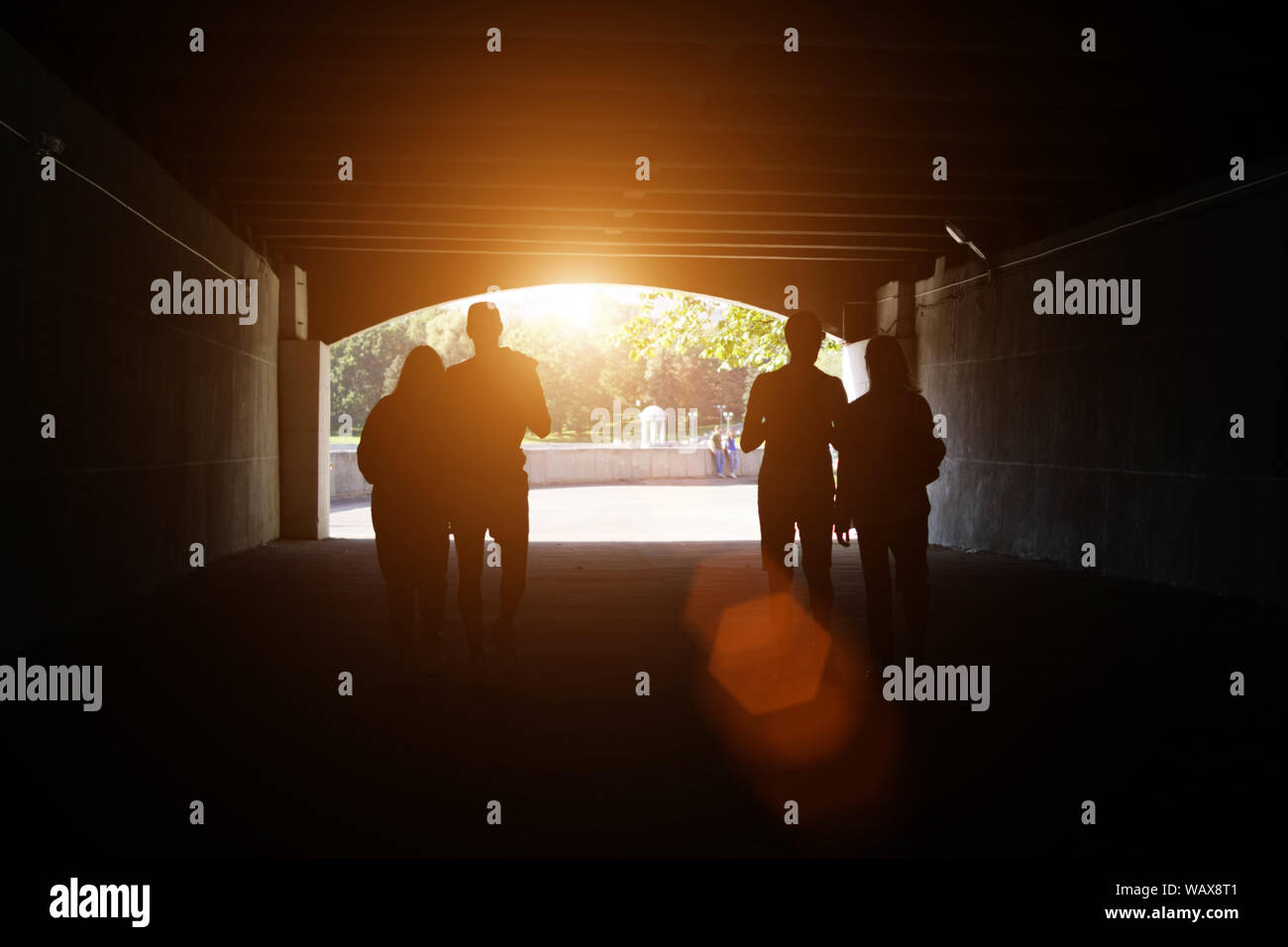 Zwei Paare von Random unkenntlich Menschen gehen durch den Tunnel im Park. Und ein anderes Paar bleibt hinter Ihnen auf dem Hintergrund. Stockfoto