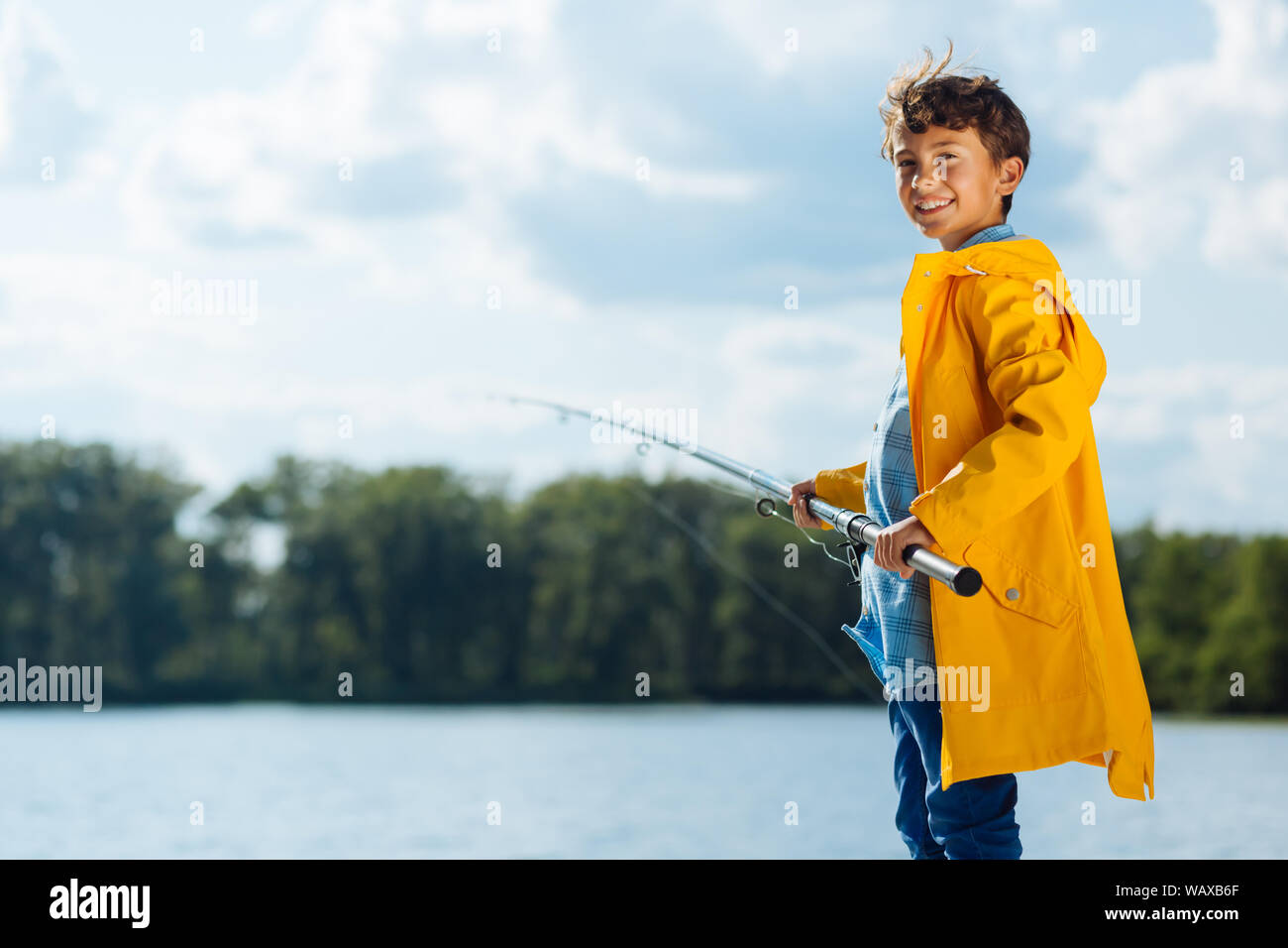 Junge tragen gelbe Regenjacke Lächeln beim Angeln Stockfoto