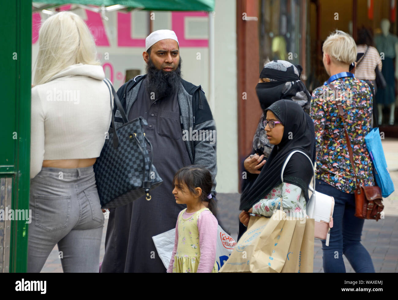 Blonde Mädchen & muslimischen Familie, in der fast food Stall. Stockfoto